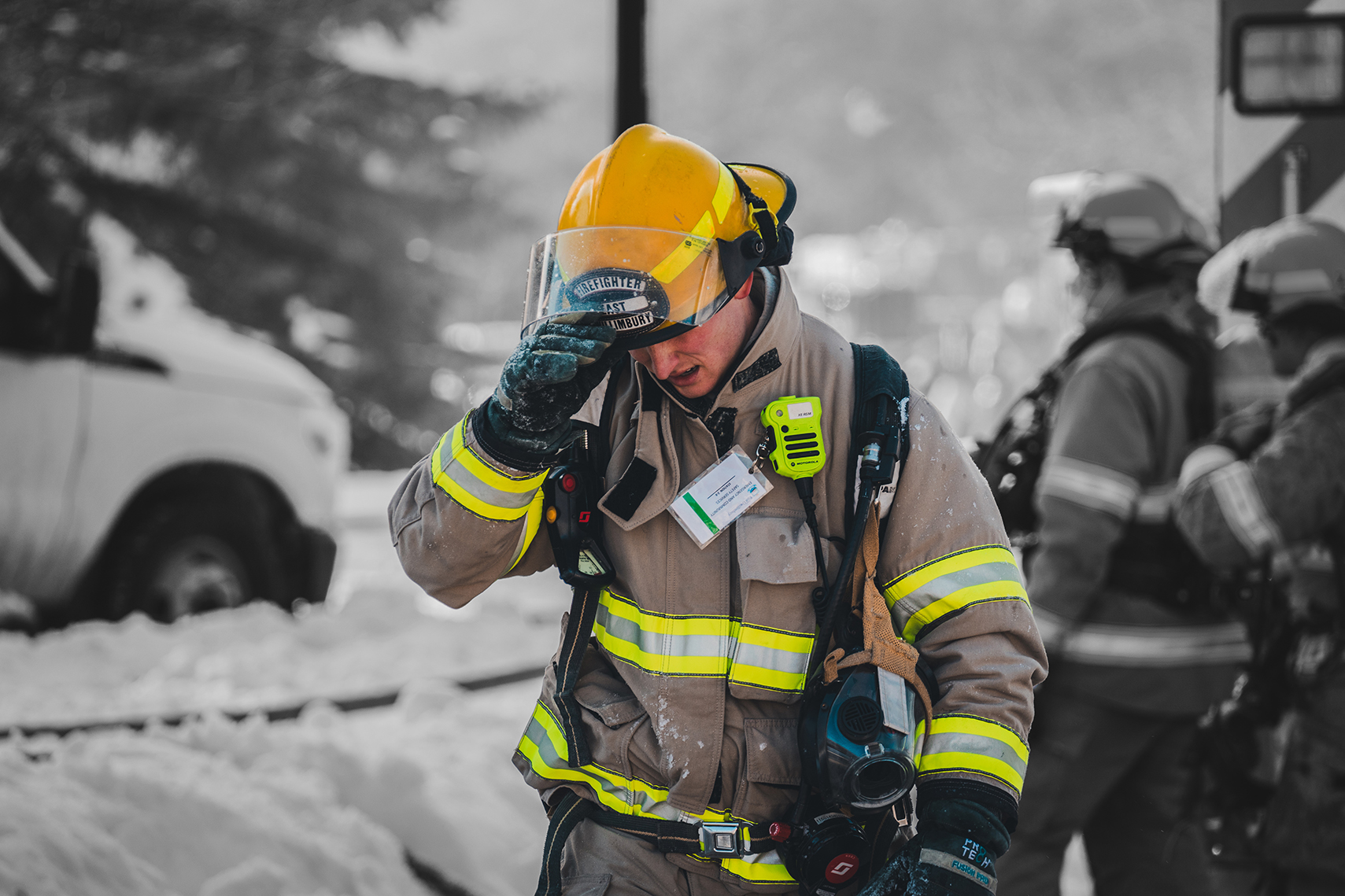 a firefighter at a scene walks with their head down toward the viewer